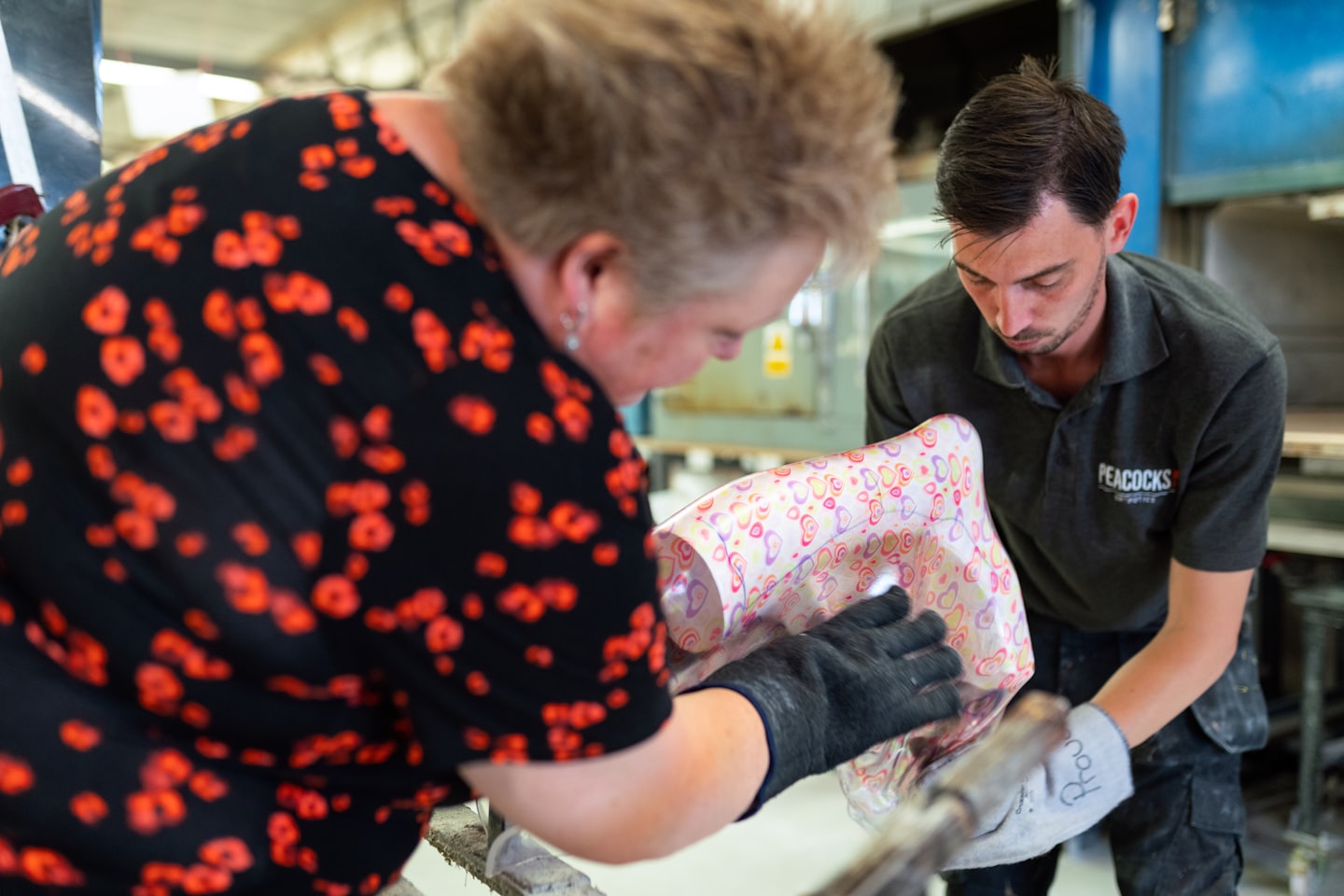 Workers collaborate on molding a heart-patterned object.