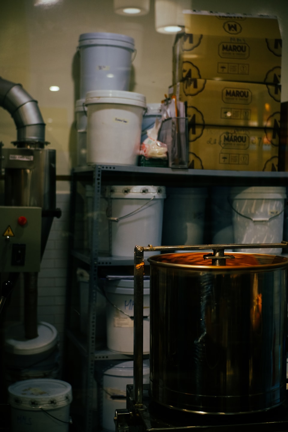Industrial processing machines sit near shelves stocked with plastic buckets.
