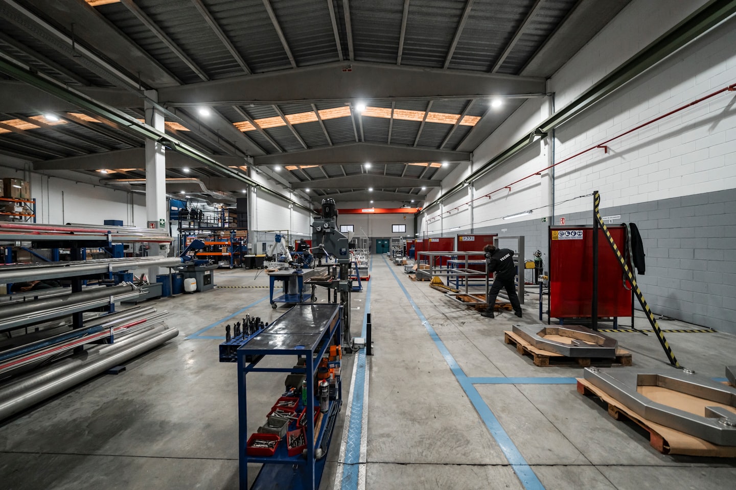 Worker assembling metal components on a pallet in a workshop.