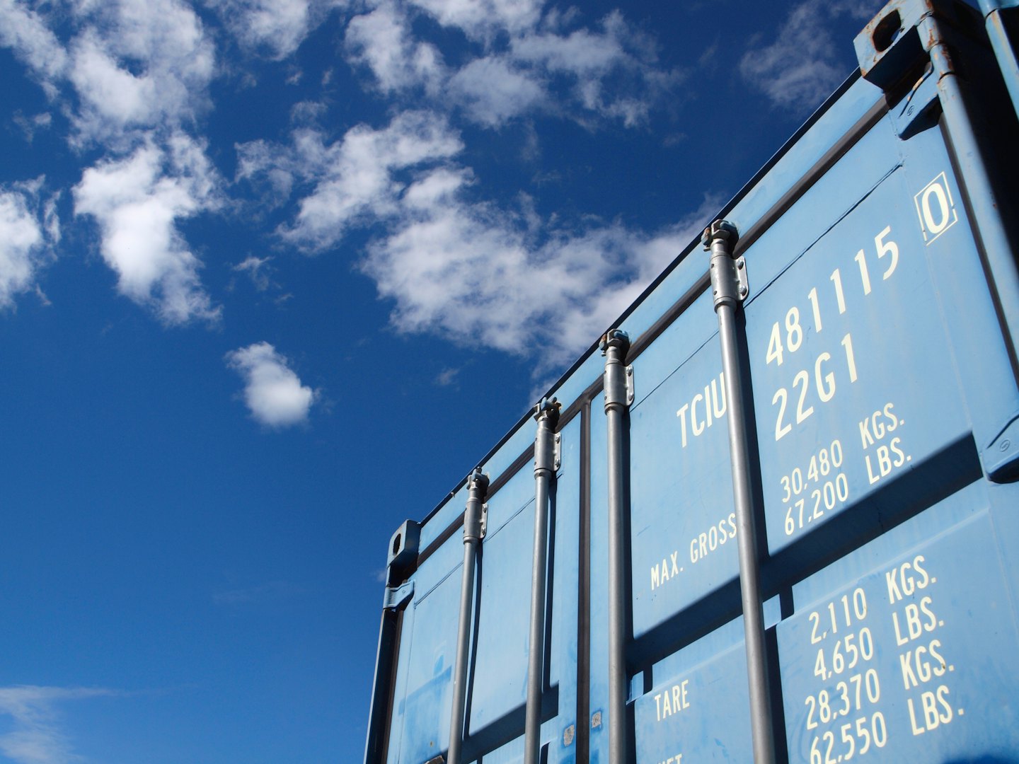 Blue shipping container against a clear sky.