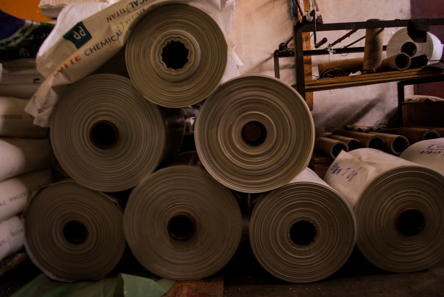 Large white rolls of material stacked in a warehouse.